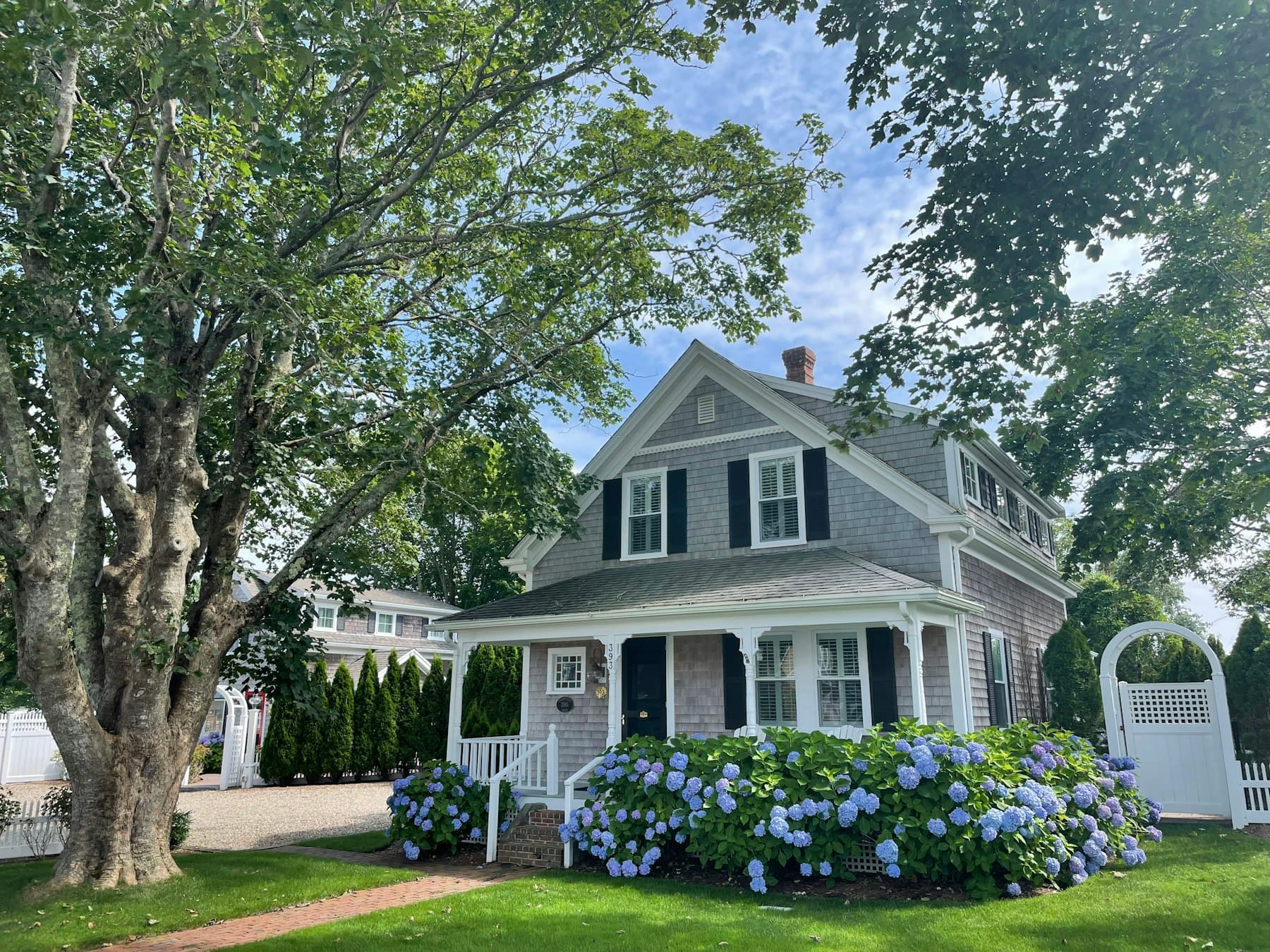 Well-kept two-story home with a covered porch and blooming hydrangeas